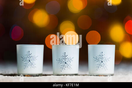 Ensemble de 3 bougies debout dans la neige avec defocused fairy lights, orange ou jaune à l'arrière-plan flou, christmas background with copy space Banque D'Images