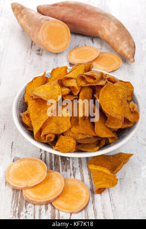 Fried et matières premières puces batata rouge sur la table en bois blanc. Banque D'Images