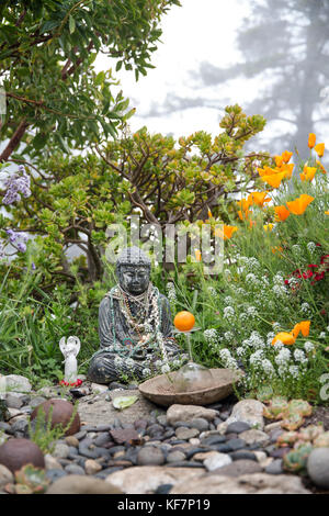 États-unis, Californie, big sur, esalen, orné d'un bouddha offrandes repose sous un arbre dans le jardin de bouddha Banque D'Images