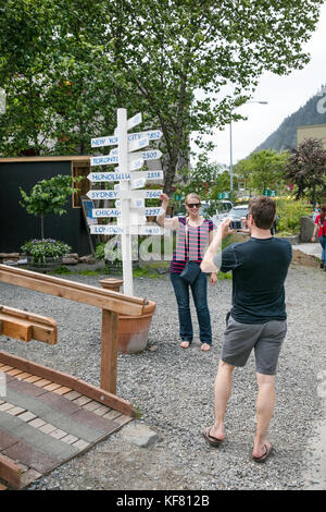 Usa, Alaska, Juneau, une femme pose à côté d'un mile marker dans le centre-ville de juneau Banque D'Images