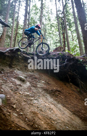 Canada, Vancouver, Colombie-Britannique, mountain biker Andrew Baker obtient l'air sur un sentier dans la forêt tropicale, north vancouver Banque D'Images