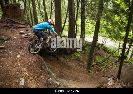 Canada, Vancouver, Colombie-Britannique, mountain biker Andrew Baker obtient l'air sur un sentier dans la forêt tropicale, north vancouver Banque D'Images