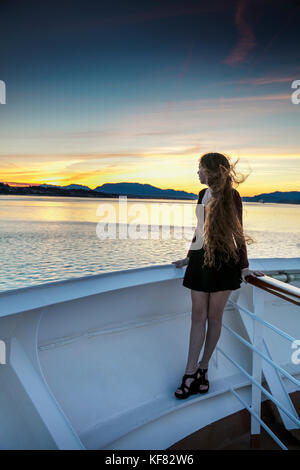 Canada, Vancouver (C.-B.), une jeune femme regarde le coucher du soleil des passagers sur le navire de croisière Holland America, l'Oosterdam escales croisières, tandis qu'il l'intérieur pas Banque D'Images