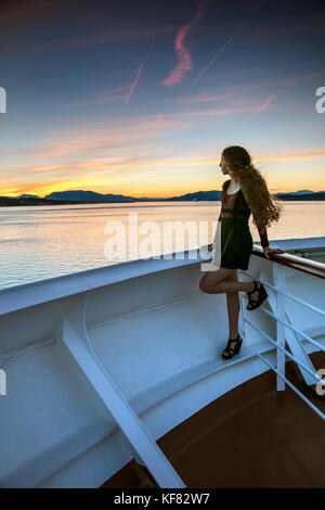 Canada, Vancouver (C.-B.), une jeune femme regarde le coucher du soleil des passagers sur le navire de croisière Holland America, l'Oosterdam escales, bien qu'il passe à l'intérieur des croisières Banque D'Images