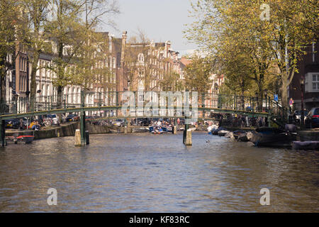 Vue depuis le niveau d'eau d'un canal dans une ville animée, avec des gens se rassemblant sur un pont en arc. Banque D'Images