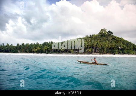L'Indonésie, les îles Mentawai, kandui left Surf resort, l'homme natif dans une pirogue avec des palmiers à l'arrière-plan, de l'océan indien Banque D'Images