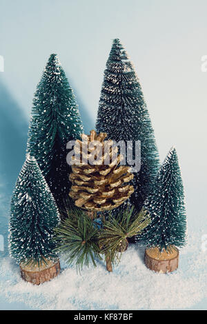 Photographie vintage plein de sapins artificiels filtrée comme une petite forêt enneigée arbre avec une pomme de pin avec sa succursale peint en or à l'intérieur d'un vibra Banque D'Images