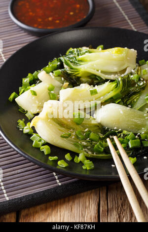 Épicé sauté de bok choy bébé gros plan sur une assiette et une sauce chili douce vertical. Banque D'Images