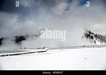 Usa, Wyoming, Yellowstone National Park, les visiteurs du parc à pied le long du cratère geyser excelsior boucle dans l'hiver, la vapeur de l'Excelsior geyser crat Banque D'Images