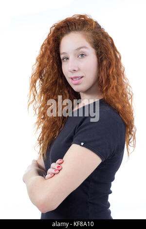 Teen avec bras croisés. jeune femme est confiante et sereine. regardant la caméra. la personne est jeune et rousse. fond blanc. chemise noire. Banque D'Images