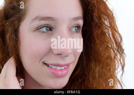 Jeune femme est à la recherche sur le côté. close up. adolescent est intéressé par quelque chose. curiosité. la personne est jeune et rousse. fond blanc. bla Banque D'Images