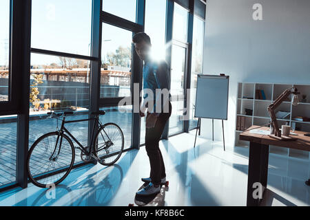 Businessman on skateboard in office Banque D'Images