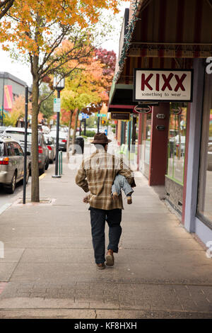 Usa (Oregon), Ashland, un homme porte son bébé sous le bras et marche le long du trottoir sur East Main Street dans le centre-ville Banque D'Images