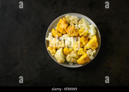 Gratin de chou-fleur jaune et blanc servi sur une plaque en céramique gris foncé sur fond de texture. Télévision avec copie espace. Restaurant menu concept. Banque D'Images