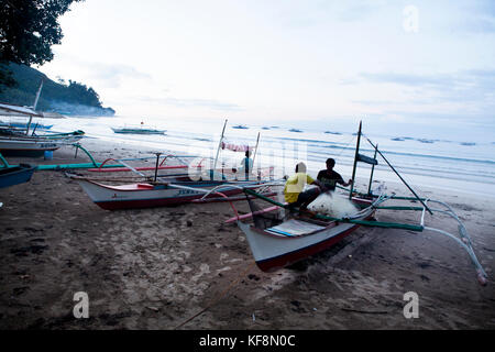 Philippines, Palawan, sabang, les pêcheurs réparer leurs filets et réparer leurs bateaux à la plage principale de la ville de sabang Banque D'Images