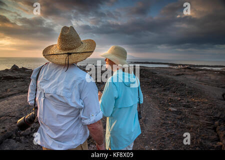 Îles Galapagos, Equateur, personnes traîner sur la plage et regarder le coucher de soleil de l'île Fernandina Banque D'Images