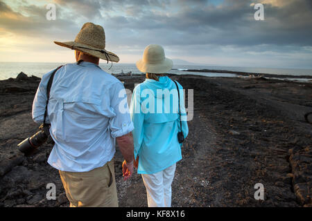 Îles Galapagos, Equateur, personnes traîner sur la plage et regarder le coucher de soleil de l'île Fernandina Banque D'Images