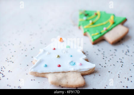 Deux gingerbread cookies en forme de l'arbre de Noël vert et blanc sur l'arrière-plan d'une table en bois et graines de chia dispersés. Banque D'Images