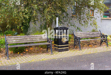 Deux bancs de parc délabrés et un bac à litière de city council sur le bord de la route dans le petit village de moulin d'Edenderry à Belfast, en Irlande du Nord Banque D'Images