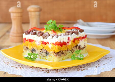 Russe traditionnelle salade mimosa en couches composé de poisson en boîte recouverte de couches de pommes de terre bouillies, carotte, oignon, fromage, oeufs et de la mayonnaise. Banque D'Images