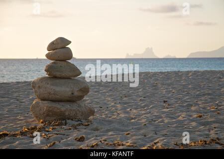 Coucher de soleil avec des piles en pierre à plage de Ses Illetes avec Es Vedrá et Ibiza îles dans l'arrière-plan de Formentera (Baléares, Espagne) Banque D'Images