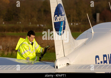 Un travailleur de l'aéroport portant un tabard jaune un ravitaillement Cabair Piper PA-28-161 Cadet avec un moteur diesel Thielert Centurion Banque D'Images