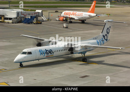 Un Flybe Bombardier DHC-8 Dash 8-400 Q400 roulait avec un Airbus A319-100 easyJet garée derrière Banque D'Images