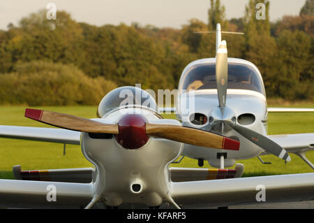 Hélice en bois sur une queue roues avions stationnés à la lumière avec un Cirrus SR-22 garé derrière Banque D'Images