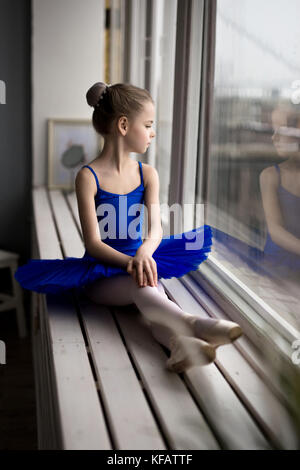 Petite fille rêve de devenir une ballerine. La jeune fille dans un costume de danse ballet bleu dans une chambre. Banque D'Images