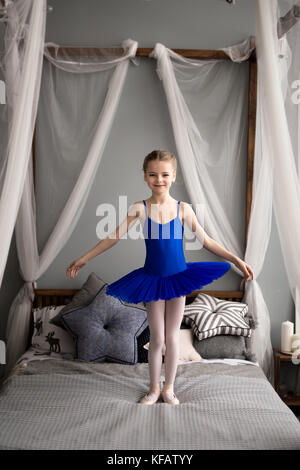 Petite fille rêve de devenir une ballerine. La jeune fille dans un costume de danse ballet bleu dans une chambre. Banque D'Images