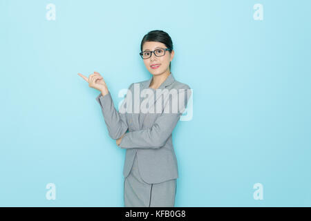 Happy woman banker droit debout dans blue wall background social et de pointage de vide avec le sourire. Banque D'Images