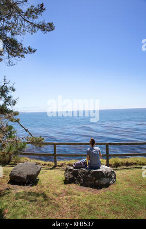 États-unis, Californie, big sur, esalen, une femme se repose sur un rocher et jouit de la vue sur l'océan pacifique Banque D'Images