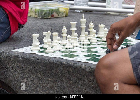 Un homme part déplacer un pion sur une partie d'échecs sur la rue, San Francisco, californnia. Banque D'Images
