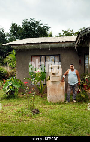 L'île de Pâques, chili, Isla de Pascua, rapa nui, un homme se tient devant sa maison à côté d'une statue moai dans Hanga Roa Banque D'Images