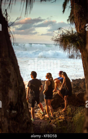 Hawaii, Oahu, côte-nord, spectateurs de regarder un grand rouleau de houle dans au coucher du soleil à pupukea Beach Park sur la Côte-Nord Banque D'Images