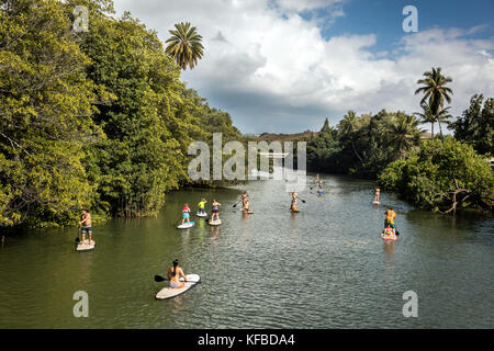 Hawaii, Oahu, côte-nord, les voyageurs paddleboarding sur l'anahulu River au-dessous du pont en arc-en-ciel historique dans la ville de haliewa Banque D'Images