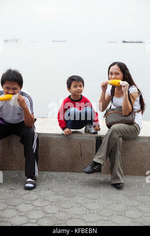 Philippines, Manille, famille bénéficie de certains maïs à la baie à pied rojas blvd Banque D'Images