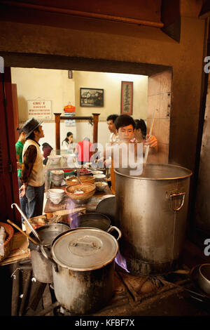 Vietnam, Hanoi, restaurant pho gia truyen, également connu sous le nom de 49 bat dan, un jeune garçon sert dans un bol de bouillon Banque D'Images