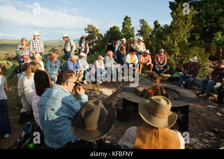 USA, Wyoming, du cantonnement, réduite à un ranch s'asseoir autour d'un feu de camp et d'écouter un homme jouer de la guitare et chanter des chansons country western, Abara Ranch Banque D'Images