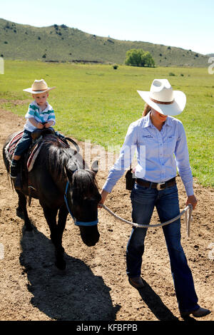 Usa, Wyoming, du cantonnement, un wrangler conduit un jeune garçon sur un poney, abara ranch Banque D'Images