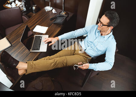 Businessman using laptop in headphones Banque D'Images