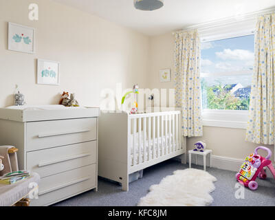 Un hôtel moderne, propre et bien rangé la pépinière de l'enfant salle décorée dans un style contemporain comprenant un lit et table à langer. Banque D'Images