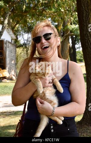 Femme jouant avec cat au cours de visite de ferme de chèvre qui fournit du lait pour door county creamery dans le comté de porte communauté de sister Bay, Wisconsin, USA. Banque D'Images