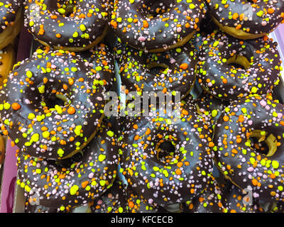 Des beignets sucrés frais en lustre de chocolat avec poudre de confiserie de couleur. studio photo Banque D'Images