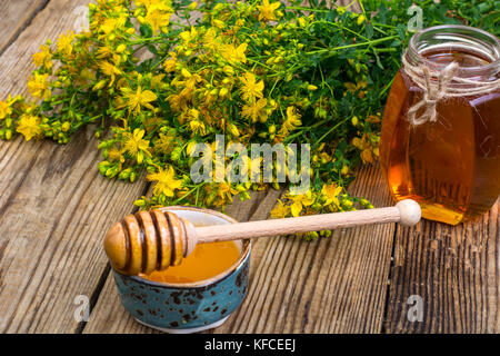 Le miel en pot de verre transparent et frais le millepertuis fleurs sur fond rustique. studio photo Banque D'Images