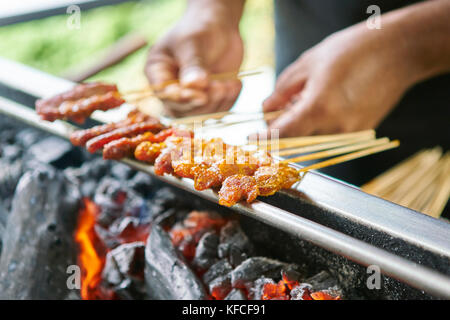 Un homme cuisine sur des coals chauds à Singapour - Satay by the Bay Banque D'Images