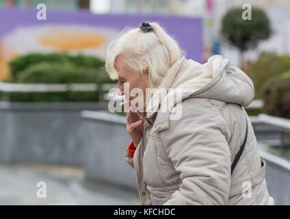 Femme âgée de race blanche fume une cigarette à l'extérieur au Royaume-Uni. Banque D'Images