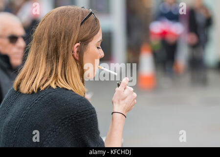 Jeune femme caucasienne éclairant une cigarette au Royaume-Uni. Style de vie malsain. Banque D'Images
