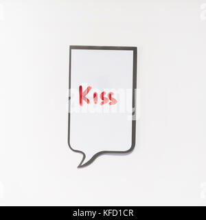 Un bloc-notes blanc ayant la forme d'une bande dessinée avec l'inscription 'Kiss' Banque D'Images