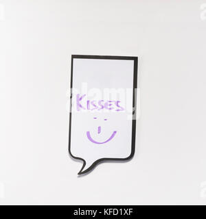 Un bloc-notes blanc ayant la forme d'une bande dessinée avec l'inscription 'kisses' Banque D'Images